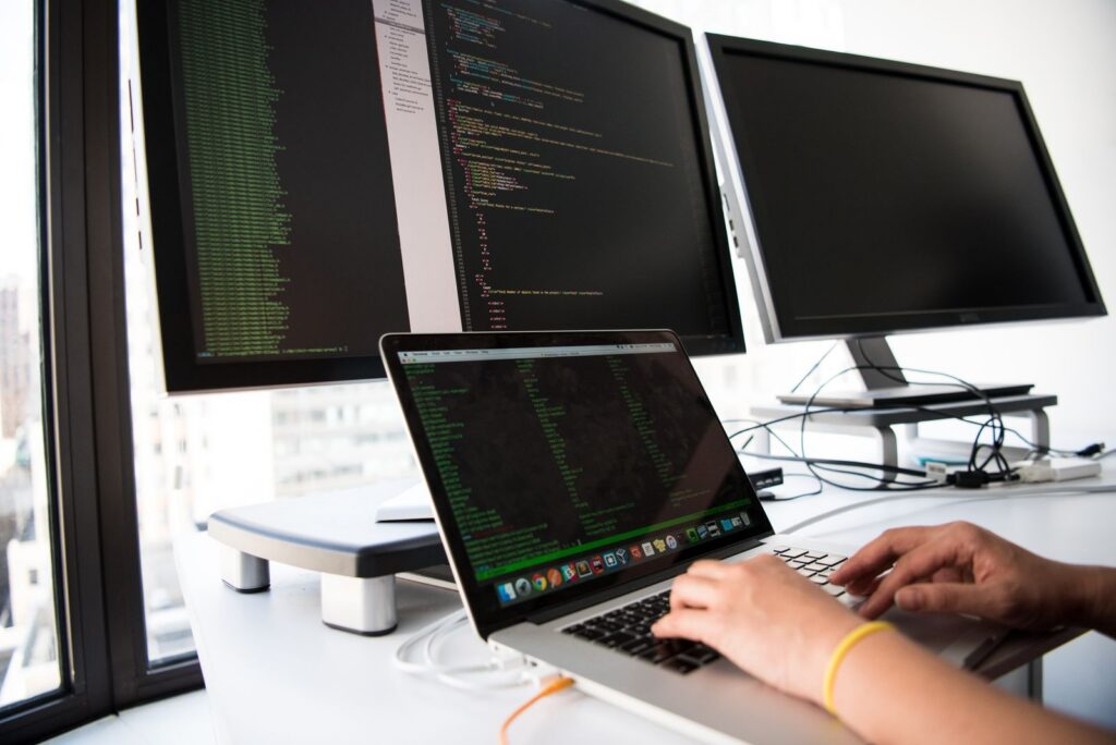 Person typing on a laptop with code on screen