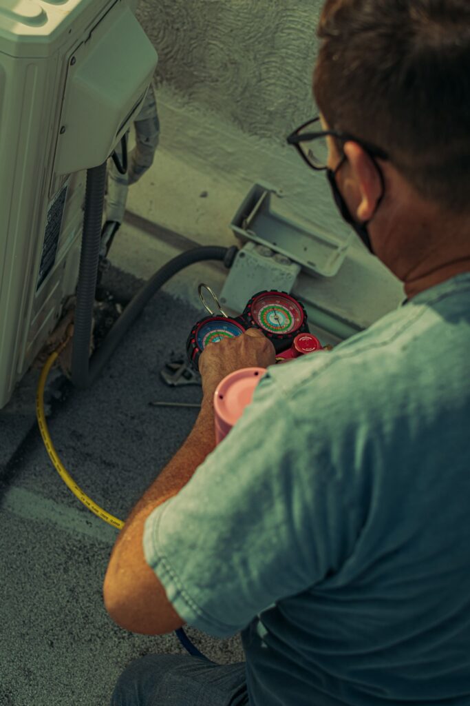 Air conditioning technician using manifold gauges to service an outdoor unit