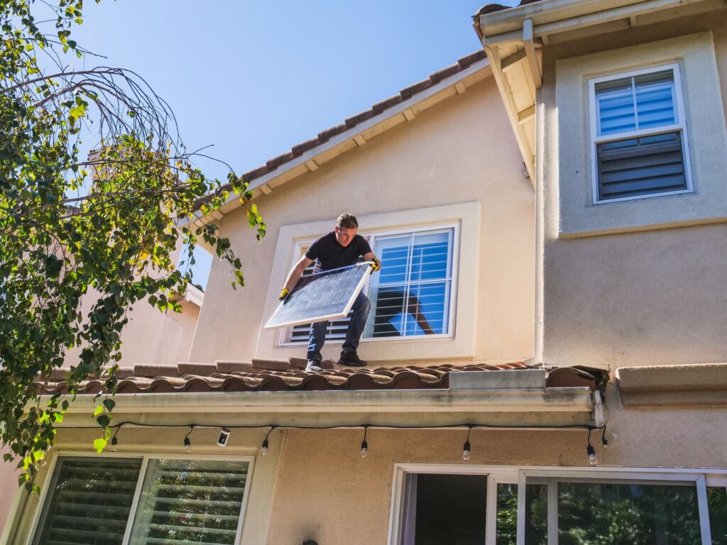 Solar panel installer carrying a panel across a residential roof
