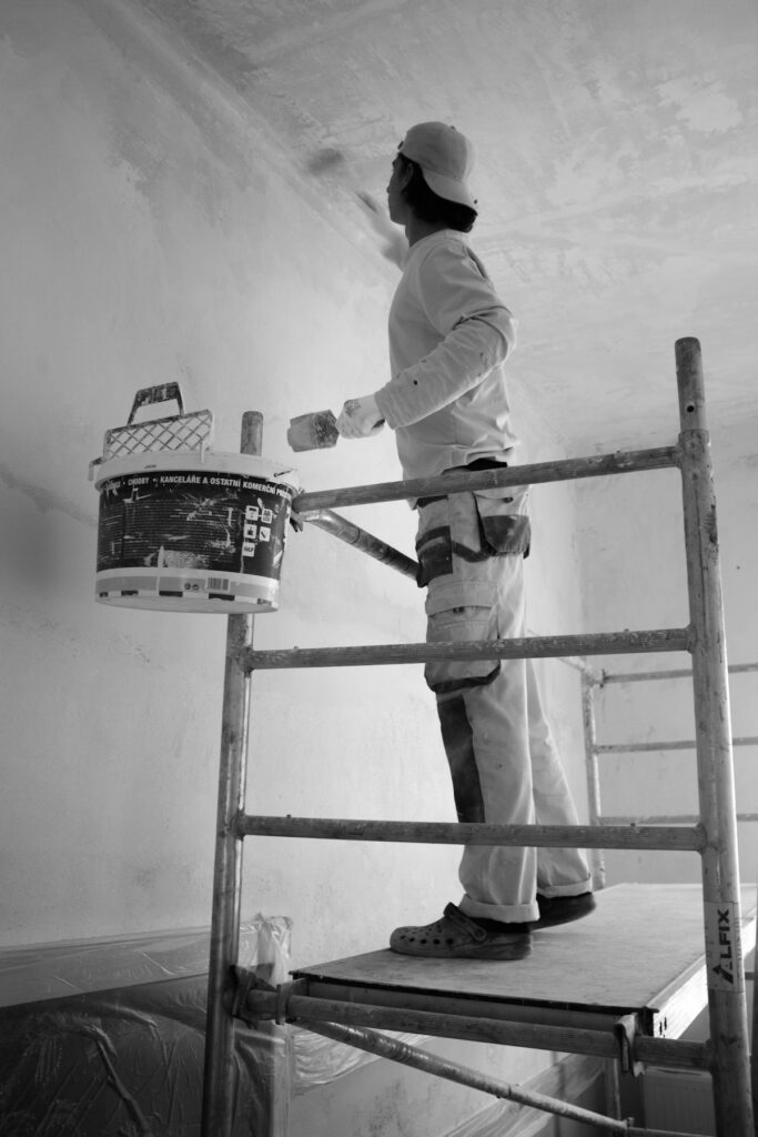 Painter applying paint to a wall with a roller, representing insurance for painters
